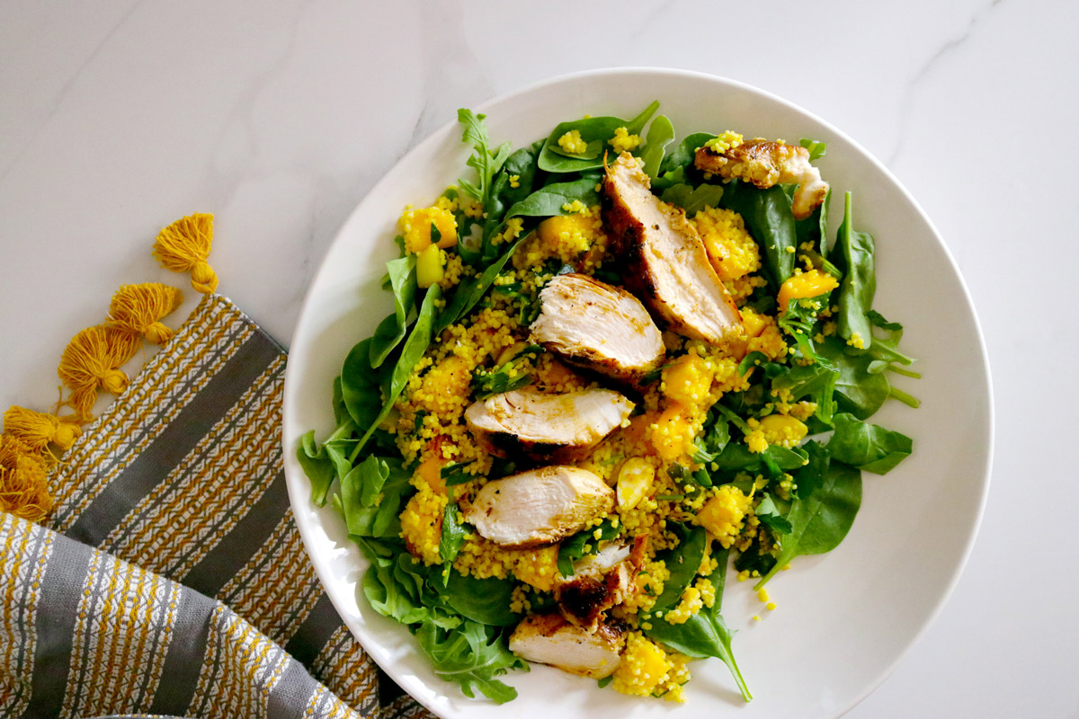 a plate of Curried Chicken Mango Couscous Salad on a marble counter top