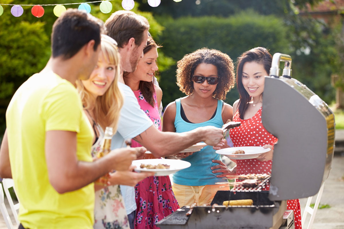 group of young people of different races and genders grilling on an outdoor patio