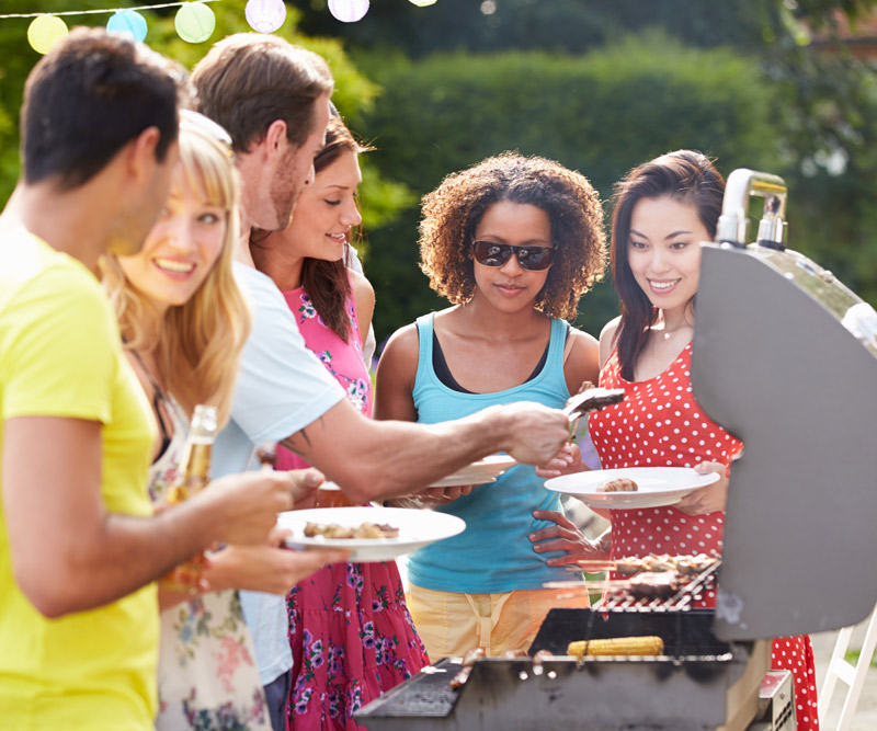 group of young people of different races and genders grilling on an outdoor patio
