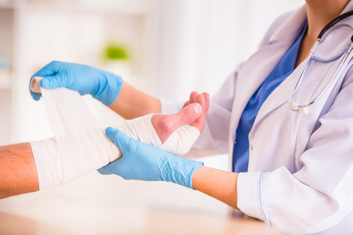 female doctor wraps a male patient's hand in a bandage