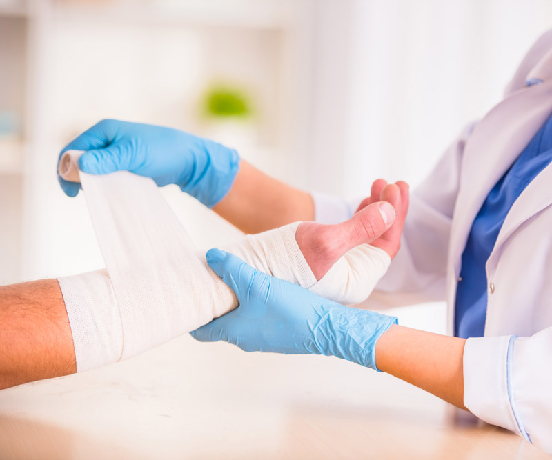 female doctor wraps a male patient's hand in a bandage