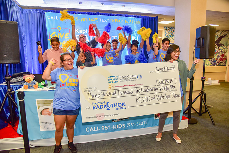 Group of children cheering and holding a ceremonial check for $300,138