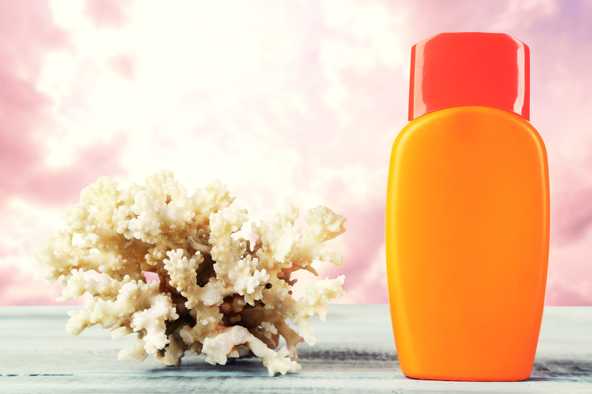 an orange bottle of sunscreen on a table next to a piece of coral