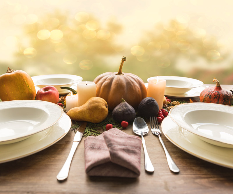 Four plates with cutlery and autumnal vegetables on wooden table