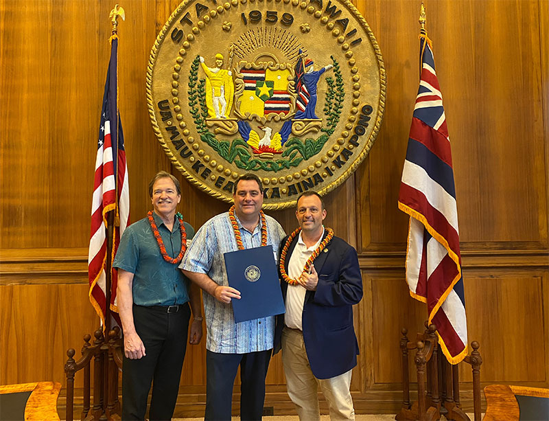 Three men standing in front of State of Hawaii seal in Hawaii Lieutenant Governor's office