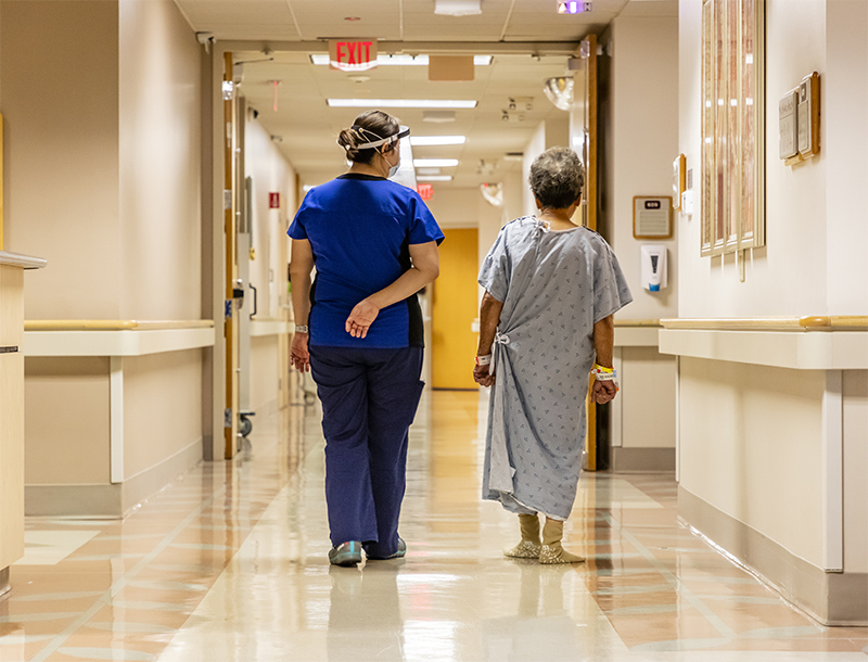 Nurse and patient walking down hospital hallway