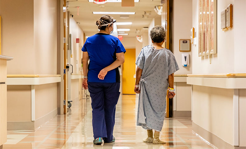 Nurse and patient walking down hospital hallway