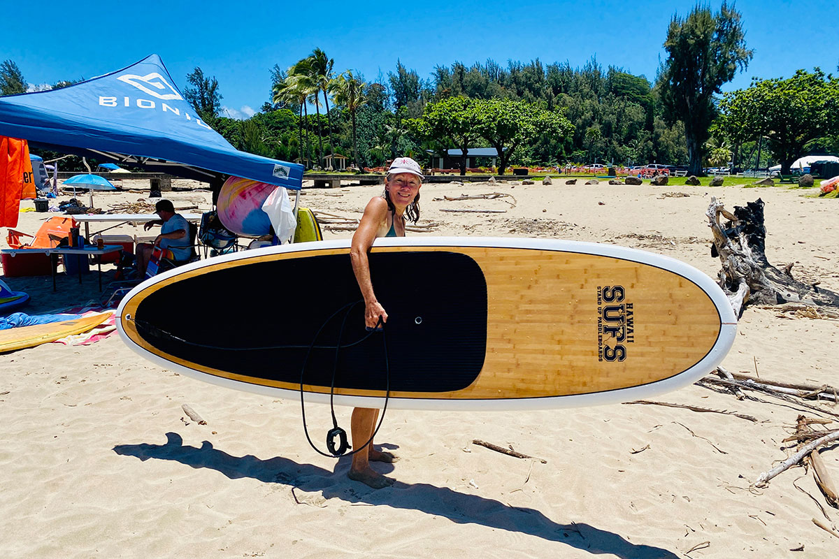 Woman carrying paddleboard on beach