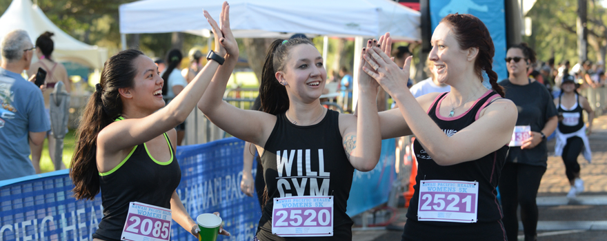 female race finishers high fiving each other