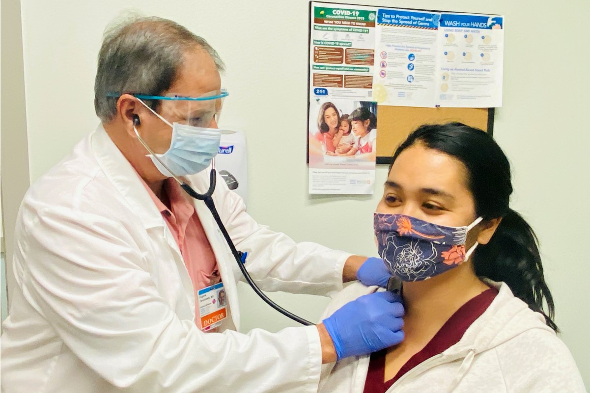 Dr. Eugene Tareshawty examining a patient with a stethoscope