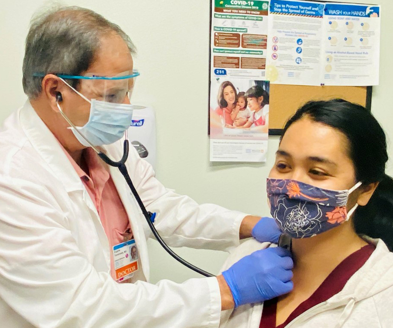 Dr. Eugene Tareshawty examining a patient with a stethoscope