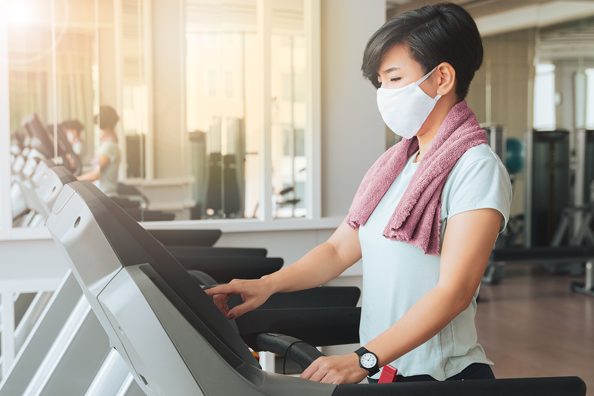 Woman wearing a mask exercising on treadmill