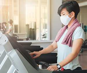 Woman wearing a mask exercising on treadmill