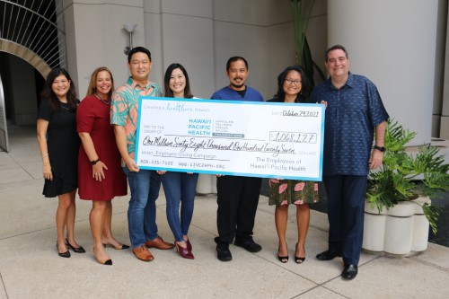 Group of seven individuals holding a ceremonial check for more than $1 million