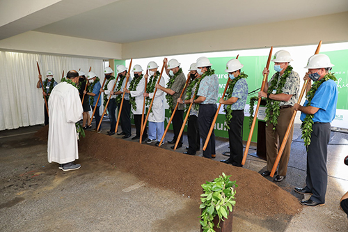 Group of people holding Hawaii o'o sticks at groundbreaking ceremony