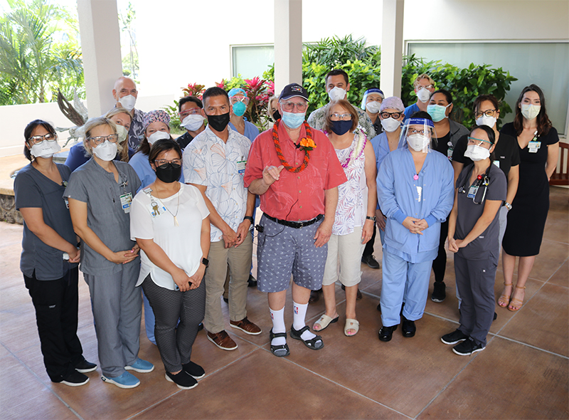 Group of health care workers and staff with former patient and wife