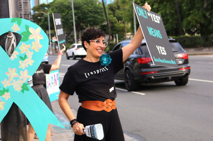 woman sign waving to promote sexual assault prevention awareness