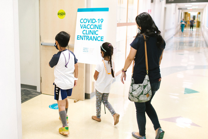 Hawaii children and parent walking into COVID vaccination clinic at Kapiolani Medical Center
