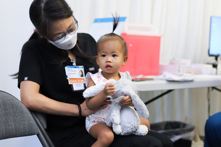 toddler on the lap of a doctor at a covid vaccination site