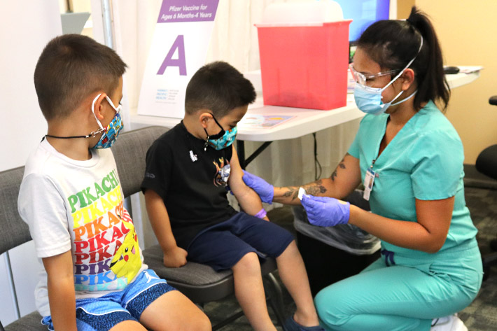 two young masked children getting vaccinated