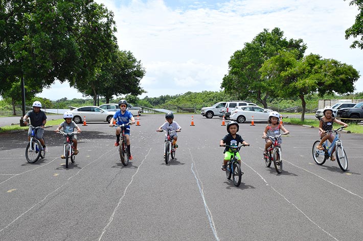 Children on bikes wearing helmets on a bike skills enhancement course at Keiki Bike & Safety Day