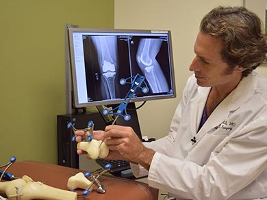 Physician demonstrates how a robotics-assisted handpiece is used for knee replacement procedures.