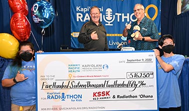 Giant check for $516,250 with Radiothon supporters including radio personalities
