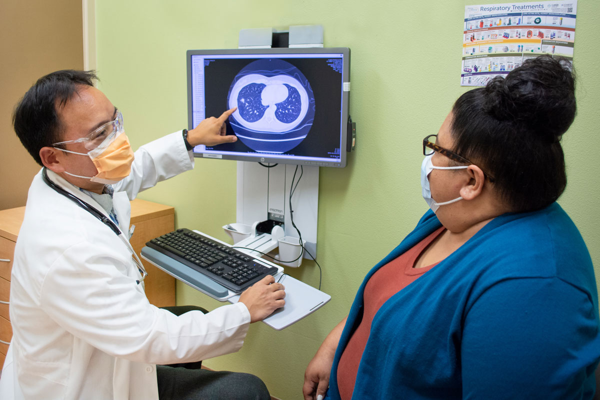 A doctor points to CT scan and talks to a patient