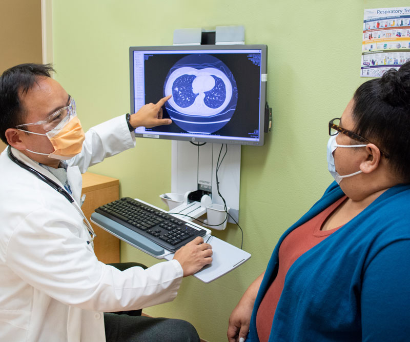 A doctor points to a CT scan and talks to a patient