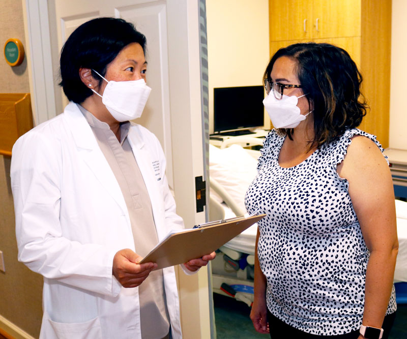 Dr. Paula Lee and oncology nurse practitioner Joanna Agena talk in the doorway of an empty exam room