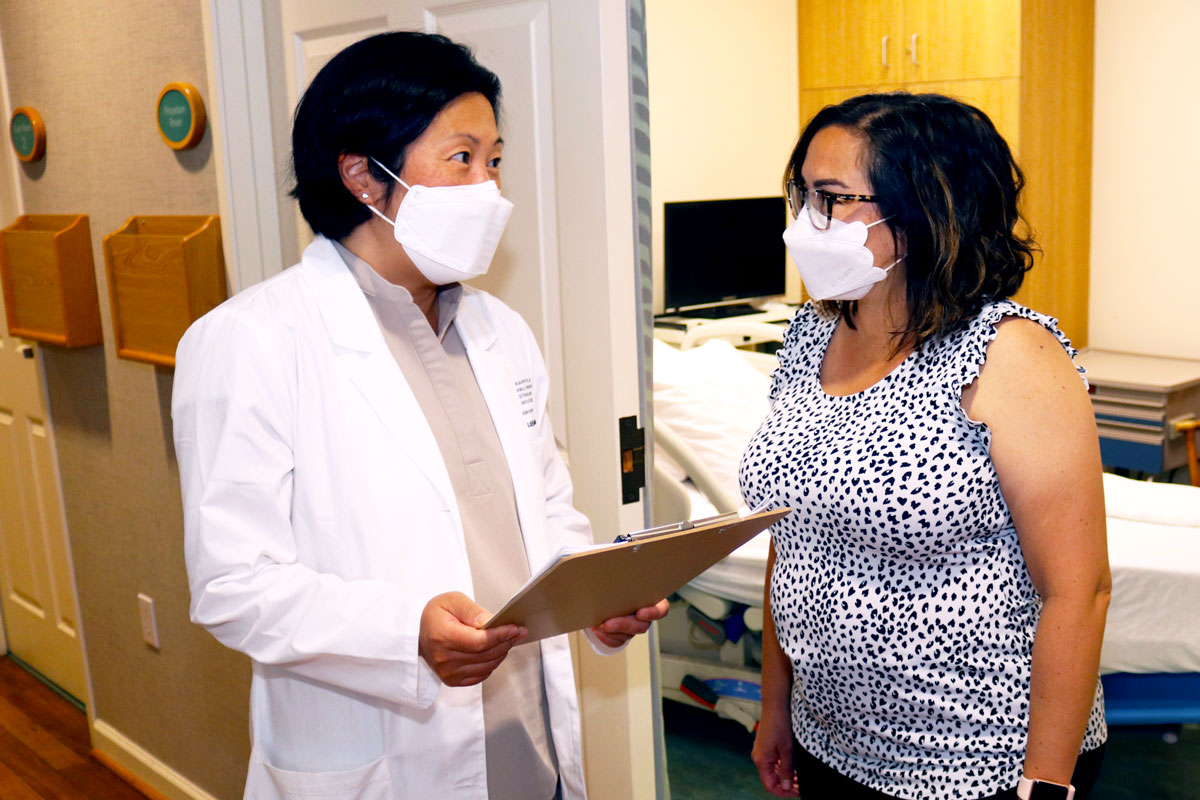 Dr. Paula Lee and oncology nurse practitioner Joanna Agena talk in the doorway of an empty exam room