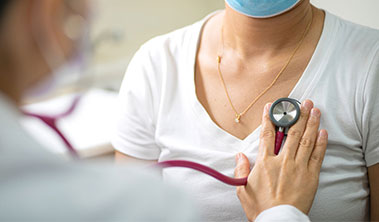 female patient and doctor holding stethoscope to her heart