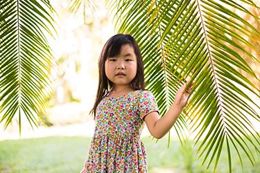 young girl under palm frond