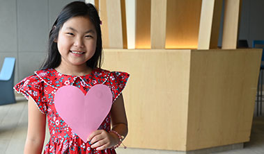 young girl holding large valentines heart