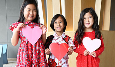 young children wearing red and holding large Valentine hearts