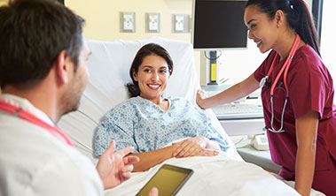 woman in hospital bed with care providers