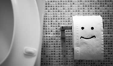Black and white image of toilet paper roll with smiley face.