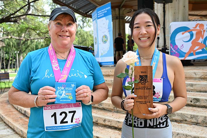 Two women runners holding awards.