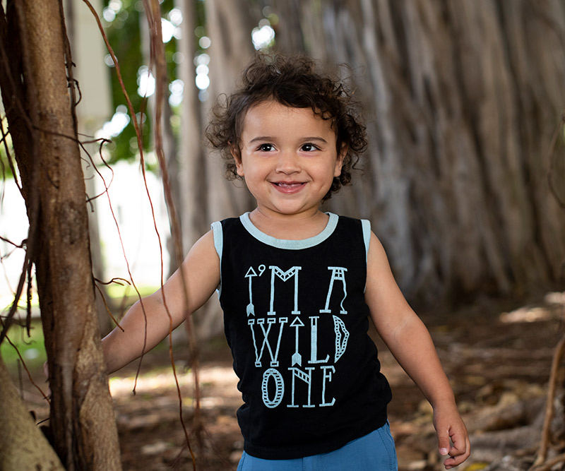 A young boy plays between the branches of a banyan tree.