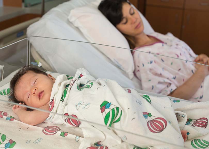 newborn sleeping beside sleeping mom