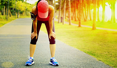 woman in fitness clothing leaning forward in exhaustion