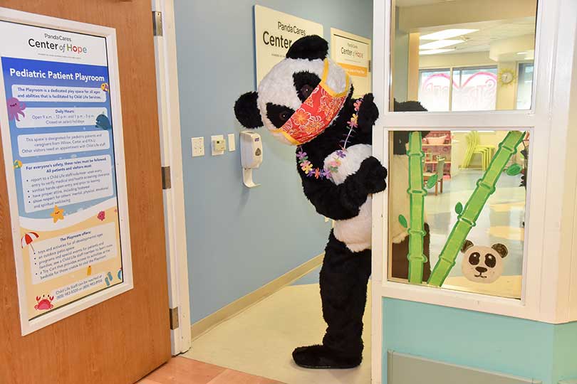 Person in panda costume peeking into hospital corrdor.