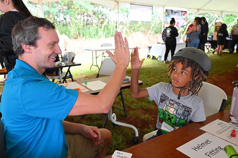 Doctor high fiving a child wearing a bike safety helmet.