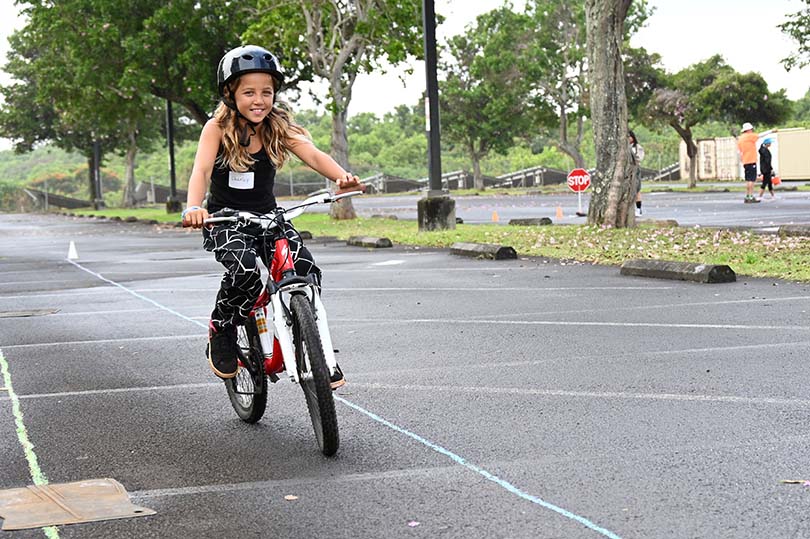 Smiling girl wearing helmet riding bicycle.