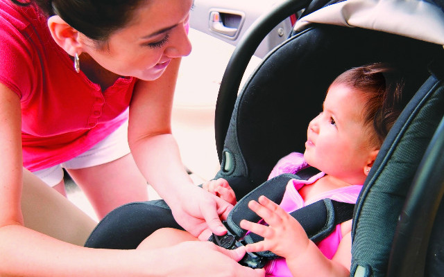 a women securing child safety seat