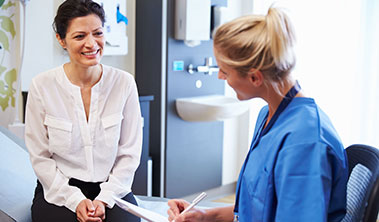 Smiling woman speaking with physician.