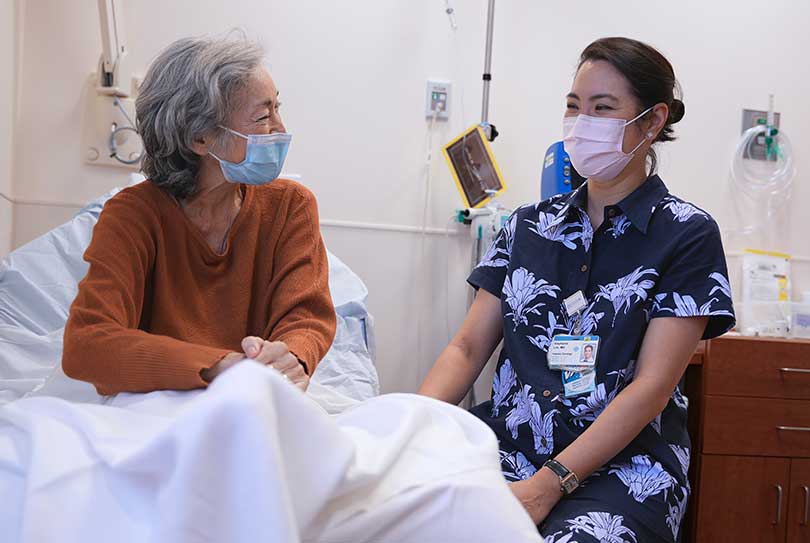 Cancer patient with doctor sitting bedside.