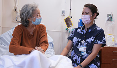 Cancer patient with doctor at her bedside.