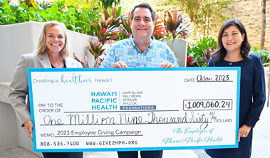 Two women and a man hold up a giant check