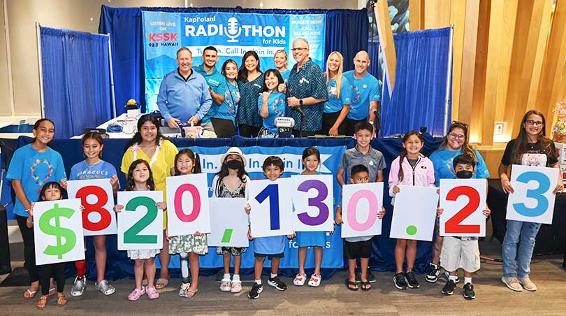 Radiothon hosts and children holding numbers showing $820,130.23